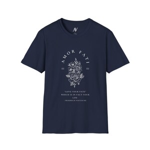 May include: Navy blue t-shirt with a white graphic print of a floral design and the text "AMOR FATI" above the flowers. The text below the flowers reads "LOVE YOUR FATE" WHICH IS IN FACT YOUR LIFE -FRIEDRICH NIETZSCHE