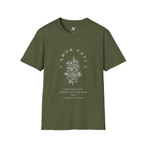 May include: A green t-shirt with a white graphic print of a floral design and the text "AMOR FATI" above the flowers. The text below the flowers reads "LOVE YOUR FATE" WHICH IS IN FACT YOUR LIFE -FRIEDRICH NIETZSCHE