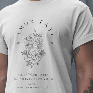 May include: A white t-shirt with a black floral design and the text "|| AMOR FATI ||" and "LOVE YOUR FATE" WHICH IS IN FACT YOUR LIFE -FRIEDRICH NIETZSCHE"