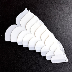 May include: A collection of white, petal-shaped tools arranged in a fan pattern. The tools have a smooth, matte finish and a small hole at the end. The background is a solid black.