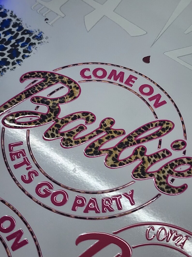May include: A pink and brown circle sticker with the text "Come on Barbie, let's go party" in a leopard print font.