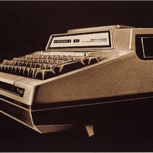 May include: A vintage Smith Corona Coronet II electric typewriter with a black and white keyboard and a beige body. The typewriter has a small display screen that reads "CORONET II" and "SMITH CORONA".