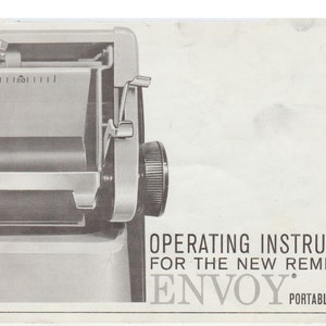 Puede incluir: Imagen en blanco y negro de las instrucciones de funcionamiento de la nueva máquina de escribir portátil Remington Envoy. La imagen muestra un primer plano del mecanismo de alimentación de papel de la máquina de escribir.