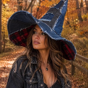 May include: A pointed hat constructed from patchwork denim fabric with frayed edges and a wide, curved brim. The underside of the brim features a red and black plaid fabric lining. The hat has a tall, conical shape with visible seams throughout.