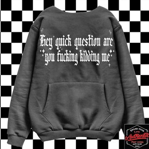 May include: A dark gray sweatshirt with a white print that reads "Hey quick question are you fucking kidding me". The sweatshirt has a kangaroo pocket and a white star design.