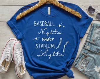 May include: A royal blue t-shirt with white text that reads "Baseball Nights Under Stadium Lights" with a baseball stitch design.