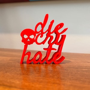 May include: Red 3D printed sign with the words "die cry hate" and a skull graphic.