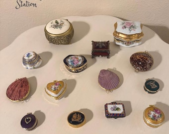 May include: A collection of vintage trinket boxes in various shapes and designs. The boxes feature floral, seashell, and animal print patterns. Some boxes are gold-trimmed, and others have intricate details. The text "Glee Vintage Station" is visible.