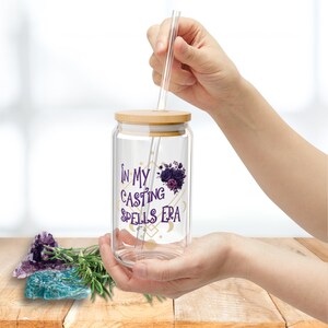 May include: A clear glass jar with a bamboo lid and a straw. The jar has a purple and gold design with the text "In My Casting Spells Era".