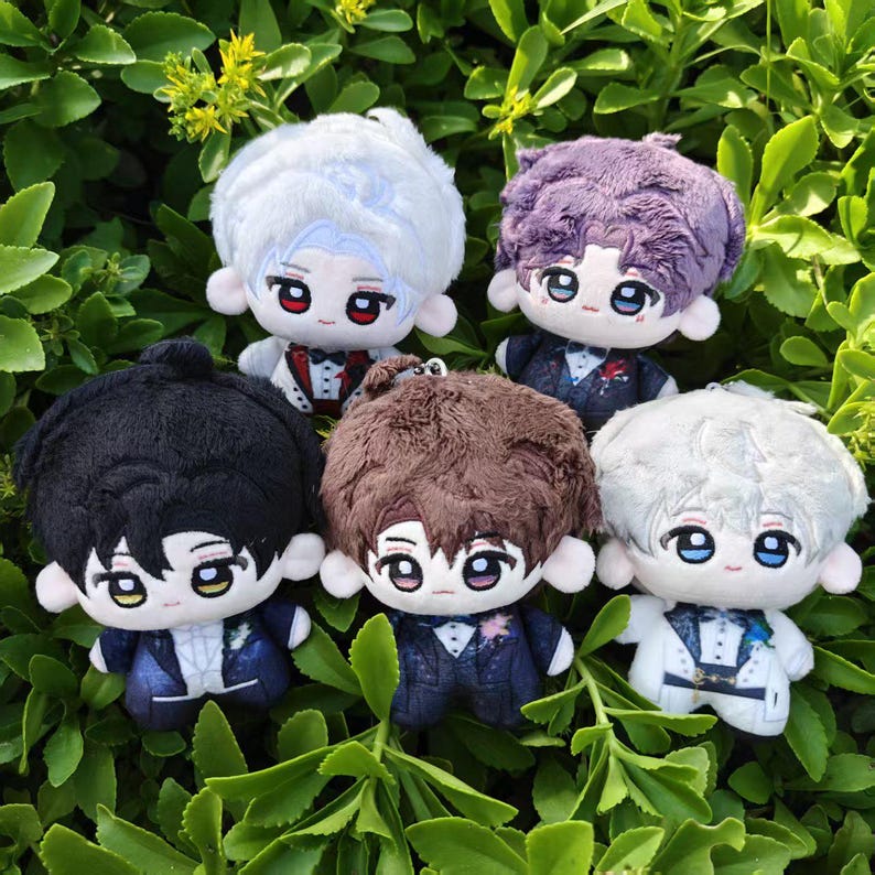 May include: Five plush dolls with different colored hair, including white, purple, black, brown, and silver. Each doll is wearing a suit with a bow tie or a decorative accent. The dolls are set against a backdrop of green foliage.