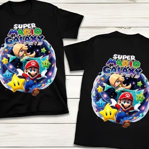 May include: Black t-shirts featuring a colorful graphic design from the Super Mario Galaxy video game. The design includes Mario, Princess Rosalina, stars, and the text "Super Mario Galaxy".