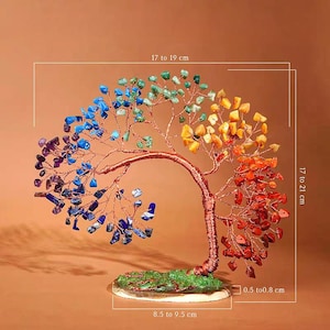 May include: A decorative tree sculpture made of copper wire and colorful gemstones. The tree's branches are adorned with blue, green, yellow, orange, and red stones. The base is 8.5 to 9.5 cm wide, and the tree is 17 to 21 cm tall.