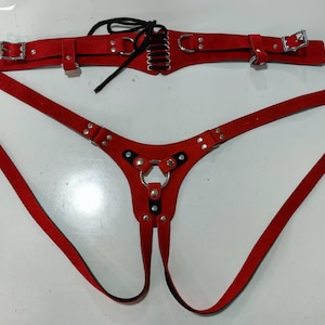 May include: Red leather harness with a metal ring and straps. The harness has a separate belt with a lace-up design.
