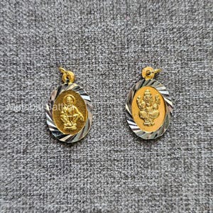 Puede incluir: Dos colgantes ovalados dorados. Cada colgante presenta una figura dorada dentro de un marco dorado, rodeada por un borde a rayas plateado y dorado. Los colgantes están sobre una superficie gris texturizada.