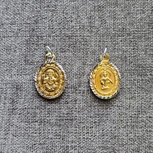 Puede incluir: Dos colgantes dorados con bordes y aros plateados. Cada colgante presenta una figura religiosa detallada en el centro. Los colgantes tienen forma ovalada y presentan diseños intrincados en los bordes.