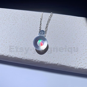 May include: A silver chain necklace with a clear glass pendant containing a small iridescent stone.