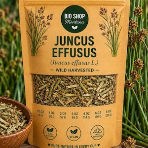 Op de afbeelding: Een bruine kraftpapieren zak met gedroogde Juncus effusus plantstukjes. Het etiket bevat de tekst BIO SHOP Montana, JUNCUS EFFUSUS, WILD HARVESTED en PURE NATURE IN EVERY CUP, met gewichtsopties variërend van 14 g tot 226 g.