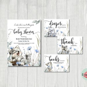 May include: A baby shower invitation set featuring a watercolor illustration of a smiling wolf cub amidst blue flowers and greenery. The invitation includes the text "Look who's new to the pack" and details for the event. Additional cards for diaper raffle, thank you, and books for baby are also included.