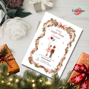 May include: A white rectangular baby shower invitation card featuring a watercolor border of pink ribbons, green holly, and red berries. The text reads A LITTLE SUGAR PLUM IS ON THE WAY, featuring a ballerina and nutcracker illustration.