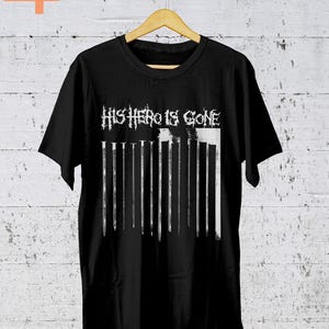Może przedstawiać: Czarny T-shirt z białym nadrukiem graficznym, na którym widnieje napis "This Hero Is Gone" w stylizowanym foncie.