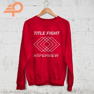 May include: Red sweatshirt with white text that reads "TITLE FIGHT" and a geometric design with the word "HYPERVIEW" below.