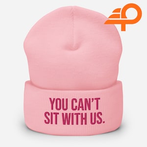 Puede incluir: Gorro de punto rosa con un dobladillo. El dobladillo tiene el texto "YOU CAN'T SIT WITH US." bordado en rosa.