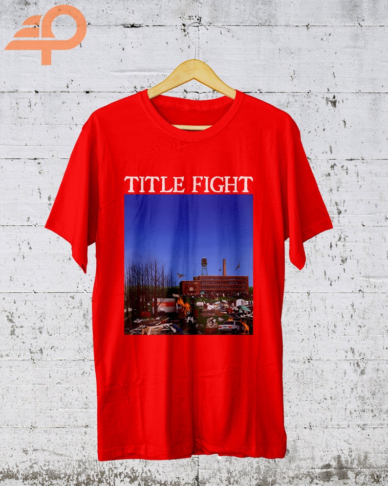 May include: Red t-shirt with a graphic print of a blue sky with a building and trees. The text "TITLE FIGHT" is printed above the graphic.