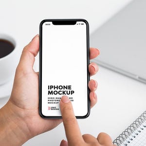 以下が含まれることがあります： 白い画面の黒いiPhoneのモックアップを手に持った人の手。画面のテキストは「IPHONE MOCKUP HIGH-QUALITY PHOTOREALISTIC 3D MOCKUP UNIC DESIGN」です。