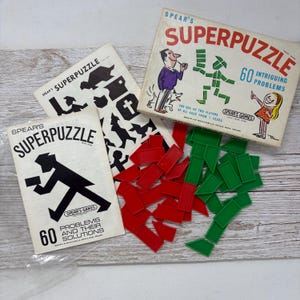 May include: A vintage Spear's Superpuzzle game box with 60 intriguing problems. The box features illustrations and text, alongside red and green puzzle pieces. Two instruction booklets are also included.