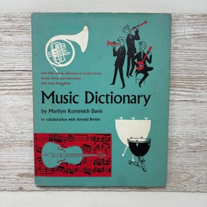 May include: A teal blue book cover with the title "Music Dictionary" by Marilyn Kornreich Davis in collaboration with Arnold Broido. The cover features illustrations of musical instruments including a French horn, a trumpet, a banjo, a violin, and a timpani.