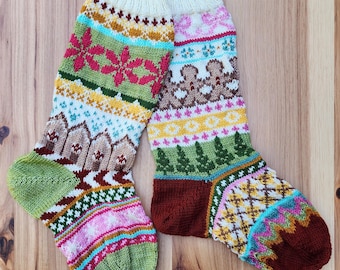 May include: A pair of colorful knitted socks with intricate patterns. The socks feature a variety of designs, including floral, geometric, and nature-inspired motifs in shades of green, pink, brown, and yellow. The socks are displayed on a wooden surface.