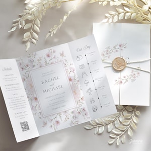 May include: A wedding invitation suite featuring a tri-fold invitation with floral designs and a wax seal. The invitation includes details, accommodations, and RSVP information. The design incorporates soft pink and white floral patterns.