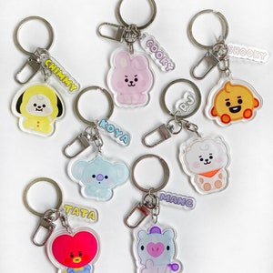 Könnte beinhalten: Satz von acht bunten Schlüsselanhängern mit Cartoon-Charakteren mit Metallringen und Anhängern. Die Charaktere stammen von der beliebten K-Pop-Gruppe BTS. Die Charaktere umfassen Chimmy, Cooky, Shooky, Koya, RJ, Tata, Mang, und  und sind alle in verschiedenen Posen.