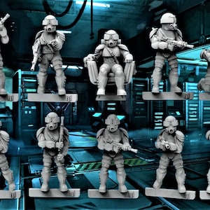 Puede incluir: Un conjunto de nueve figuras en miniatura de plástico gris de soldados que llevan cascos y máscaras de gas, sosteniendo armas. Las figuras están de pie sobre pequeñas bases grises.