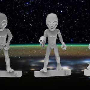 Op de afbeelding: Vijf grijze alien-figuurtjes met verschillende poses en wapens, staand op een zwart-witte achtergrond met sterren.