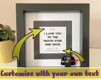 May include: A black framed picture with a white mat and a black and white print inside. The print says "Sam I love you to the Death Star and back Happy 5th Anniversary". A small black Lego figurine of Darth Vader is in the bottom right corner of the picture.
