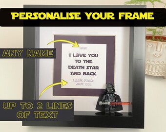 May include: A black square shadow box frame containing a white card with the text I LOVE YOU TO THE DEATH STAR AND BACK, SAM, and LOVE FROM MAX XXX. A black Darth Vader minifigure with a red lightsaber stands in the bottom right corner.