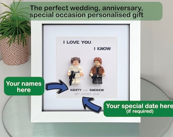 May include: A framed personalized gift featuring Lego figures of a couple, with the text "I LOVE YOU... I KNOW." The names "KIRSTY AND ANDREW" and a date are printed below the figures. The frame is white.