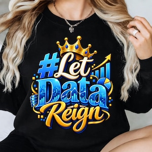 Puede incluir: Una sudadera negra de manga larga con un estampado gráfico que incluye el texto #Let Data Reign en azul y dorado. El diseño presenta una corona dorada, un gráfico de barras azul y un icono de gráfico circular, con un efecto brillante.