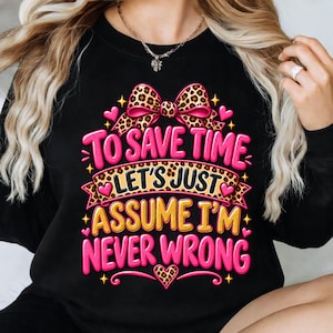 Könnte beinhalten: Ein schwarzes Langarm-Sweatshirt mit einem Grafikdesign, das eine Schleife mit Leopardenmuster und Herzen zeigt. Der Text lautet: TO SAVE TIME LET'S JUST ASSUME I'M NEVER WRONG. Die Schrift ist in Pink und Gelb mit Leopardenmuster-Akzenten.