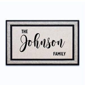 May include: Rectangular doormat with a light beige center and a black and gray border. The text "THE Johnson FAMILY" is written in black script across the center of the mat, making it a personalized home decor item.