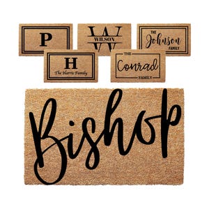 May include: A collection of rectangular tan coir doormats featuring black text and borders. The designs include single letters, family names like Wilson, Johnson, Harris, Conrad, and a large script font displaying the name Bishop.
