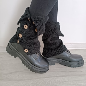 May include: Black knitted leg warmers with wooden buttons, worn over black leather boots with thick soles.