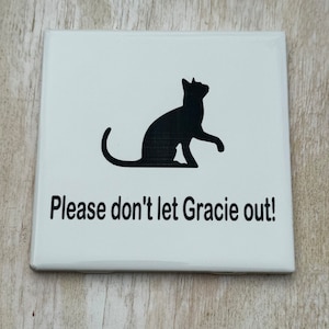 May include: White sign with a black silhouette of a cat and the text "Please don't let Gracie out!"