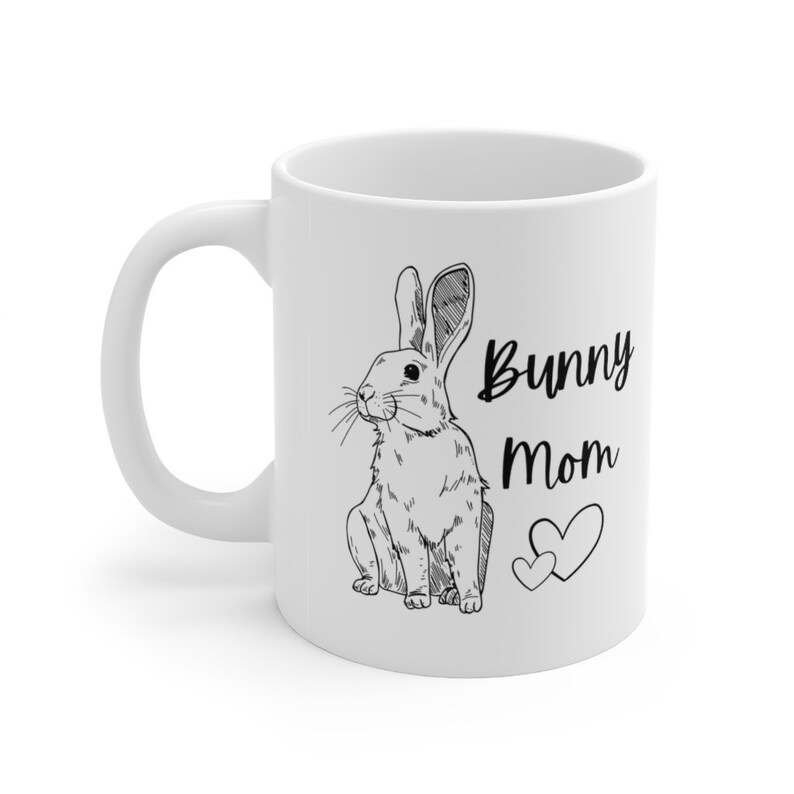 White ceramic mug with black design of rabbit and text that says "bunny mom" with two hearts.  Left handed view with handle on the left.