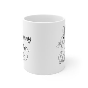 White ceramic mug with black design of rabbit that says "bunny mom" with two hearts.  Photo shows the side opposite of the handle to show that the mug has the design printed on both sides.