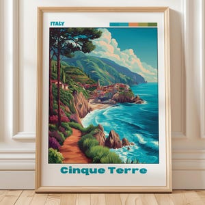 May include: A framed travel poster featuring a coastal landscape of Cinque Terre, Italy. The illustration depicts a winding path, lush green hills, colourful cliffside buildings, and blue ocean waves under a sky with white clouds. Text reads ITALY and Cinque Terre.