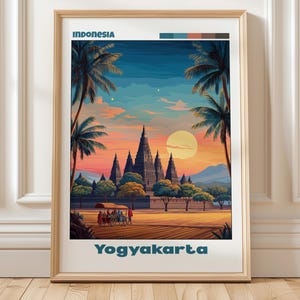 May include: A framed art print depicting an Indonesian scene with a temple, palm trees, and a sunset. The word "Indonesia" is at the top, and "Yogyakarta" is at the bottom in teal text. The artwork is in a wooden frame.