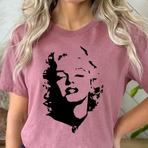May include: A mauve t-shirt with a black silhouette of Marilyn Monroe's face.