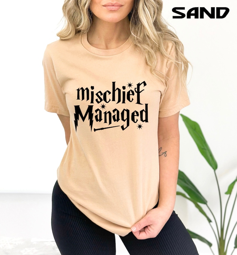 May include: A tan t-shirt with black text that reads "mischief managed" with a lightning bolt and a wand graphic.